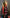 Two lit red and white striped candles in front of a decorated Christmas tree.