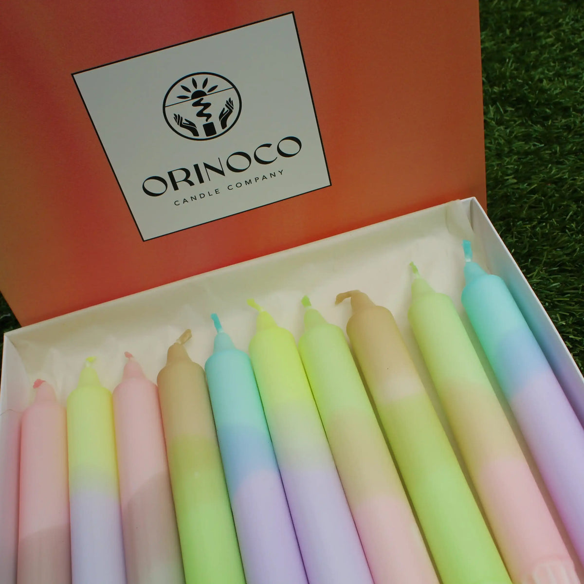 A collection of colorful pastel taper candles in an Orinoco Candle Company gift box.