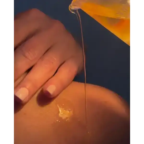 Golden therapeutic facial oil being poured onto skin for natural hydration.