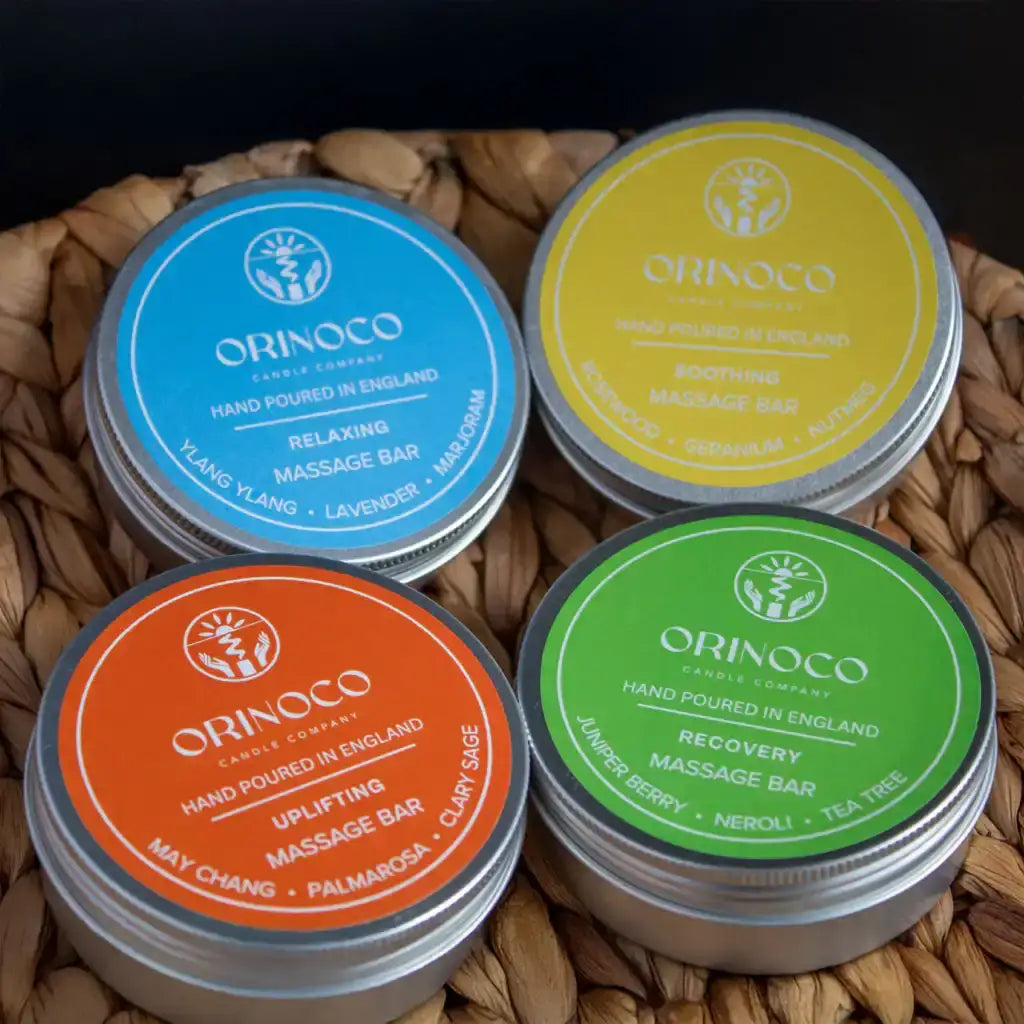 Four Orinoco tin massage bars in blue, yellow, orange, and green containers in a woven basket.
