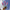 A hand holding three pink and blue gradient taper candles against a blue sky with clouds.