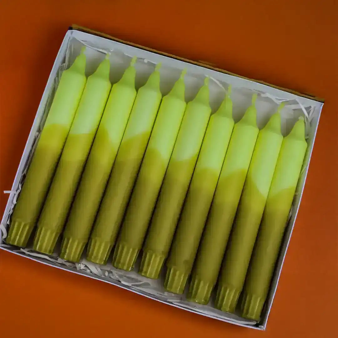 A set of dual-tone yellow and green taper candles arranged in a white gift box.
