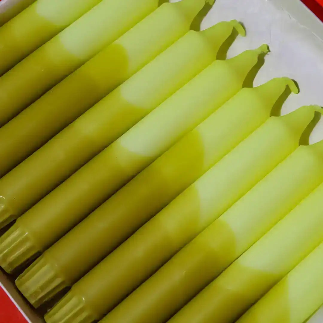 A row of light green taper candles arranged closely together.