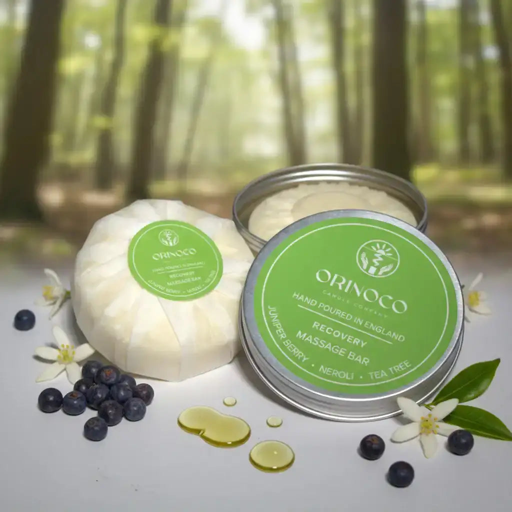 Recovery massage bar with juniper berry, neroli, and tea tree in a tin on a forest background.