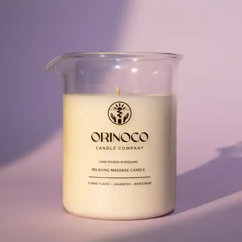 Orinoco Skincare relaxing massage candle in a clear glass jar with a purple background.