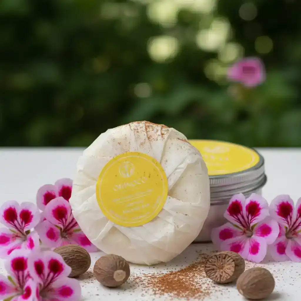 Orinoco Skincare massage bar wrapped in white paper with pink flowers and nutmeg seeds