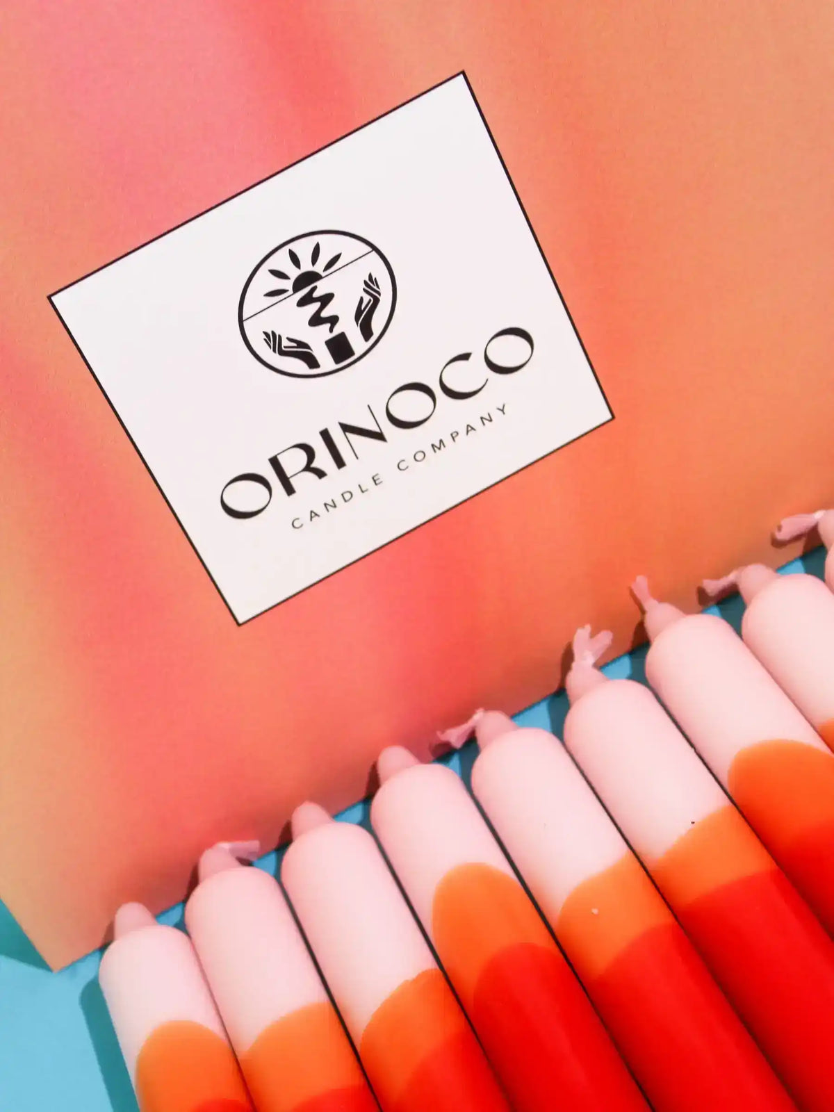 Orinoco Candle Company logo card next to orange and pink gradient taper candles.
