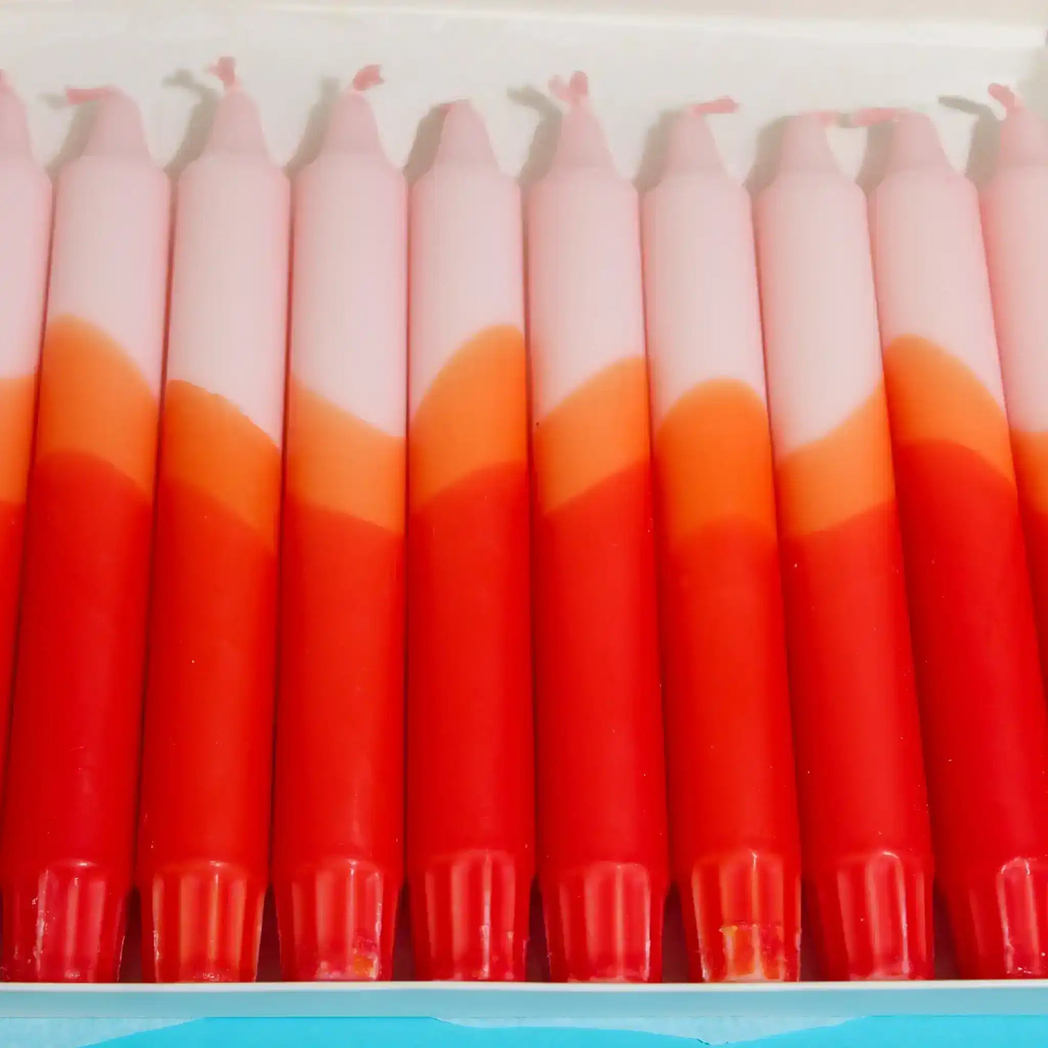 Row of gradient pink, orange, and red tapered candles.