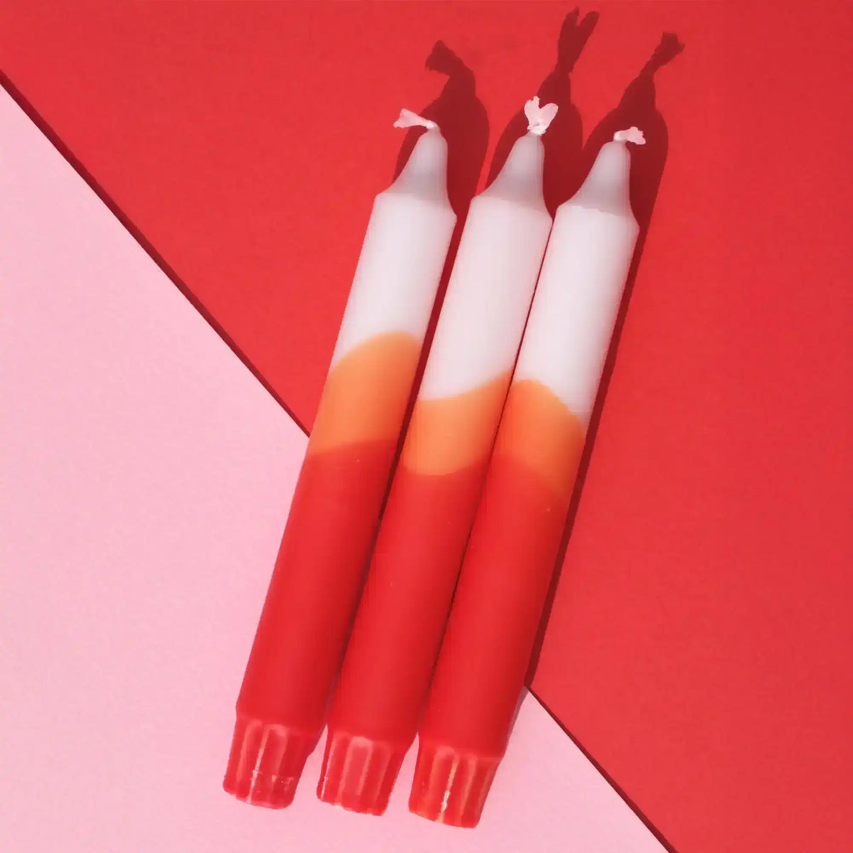 Three gradient red and white candles on a red and pink background