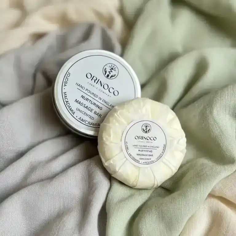Orinoco Skincare Nurturing Massage Bar and tin on soft, neutral fabric.