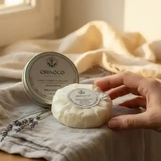 Orinoco massage bar in a tin on a neutral linen cloth with lavender sprigs.
