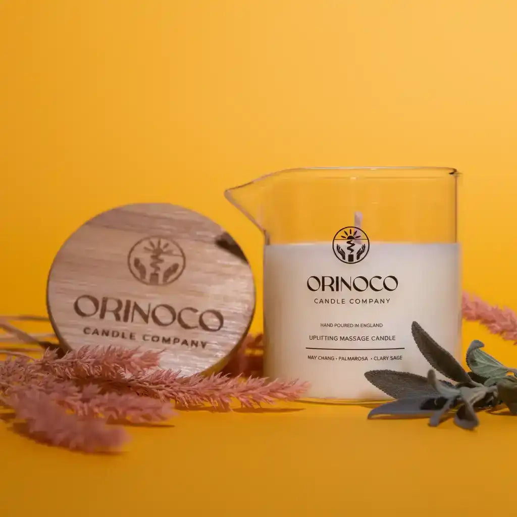 Orinoco Candle Company uplifting massage candle with a wooden lid on a yellow background.
