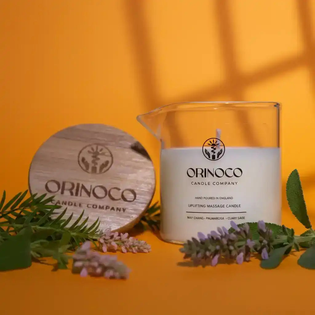 Orinoco Skincare uplifting massage candle in a glass jar with a wooden lid on an orange background.
