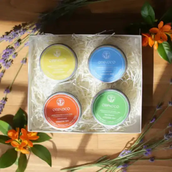 Four colorful Orinoco natural skincare tins in a gift box with dried flowers.